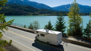 recreational vehicle driving on road by a lake