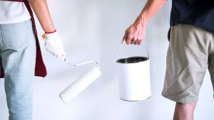 2 painters holding a paint roller and a paint can