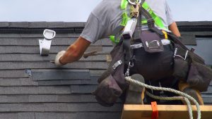 roofing contractor on roof putting shingles on home