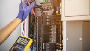 electrical technician testing power panel with voltometer