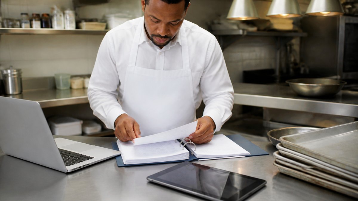 Infographic comparing catering business insurance policy options for kitchen owners on a prep table