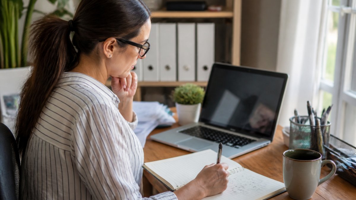 Small business owner preparing documents to request a business insurance quote on a laptop at a bright home office desk.